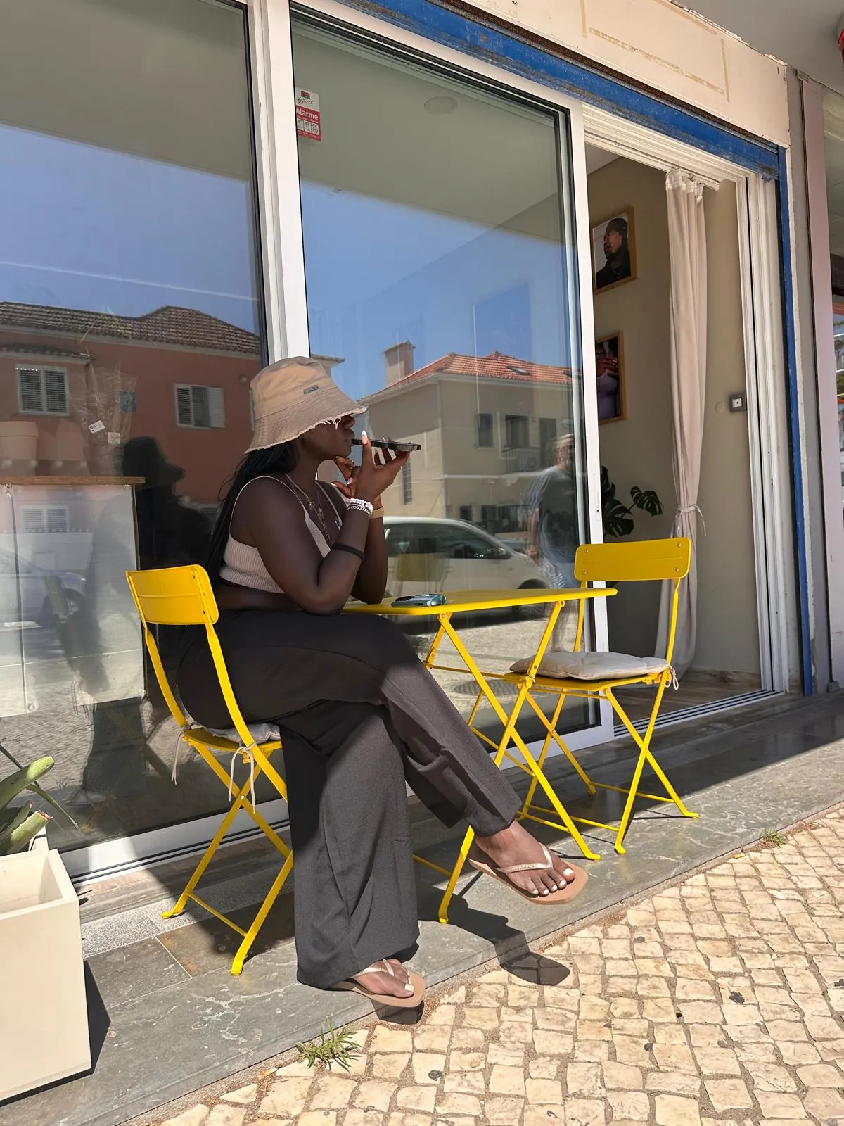 Guest sitting at the yellow bistro table outside the storefront